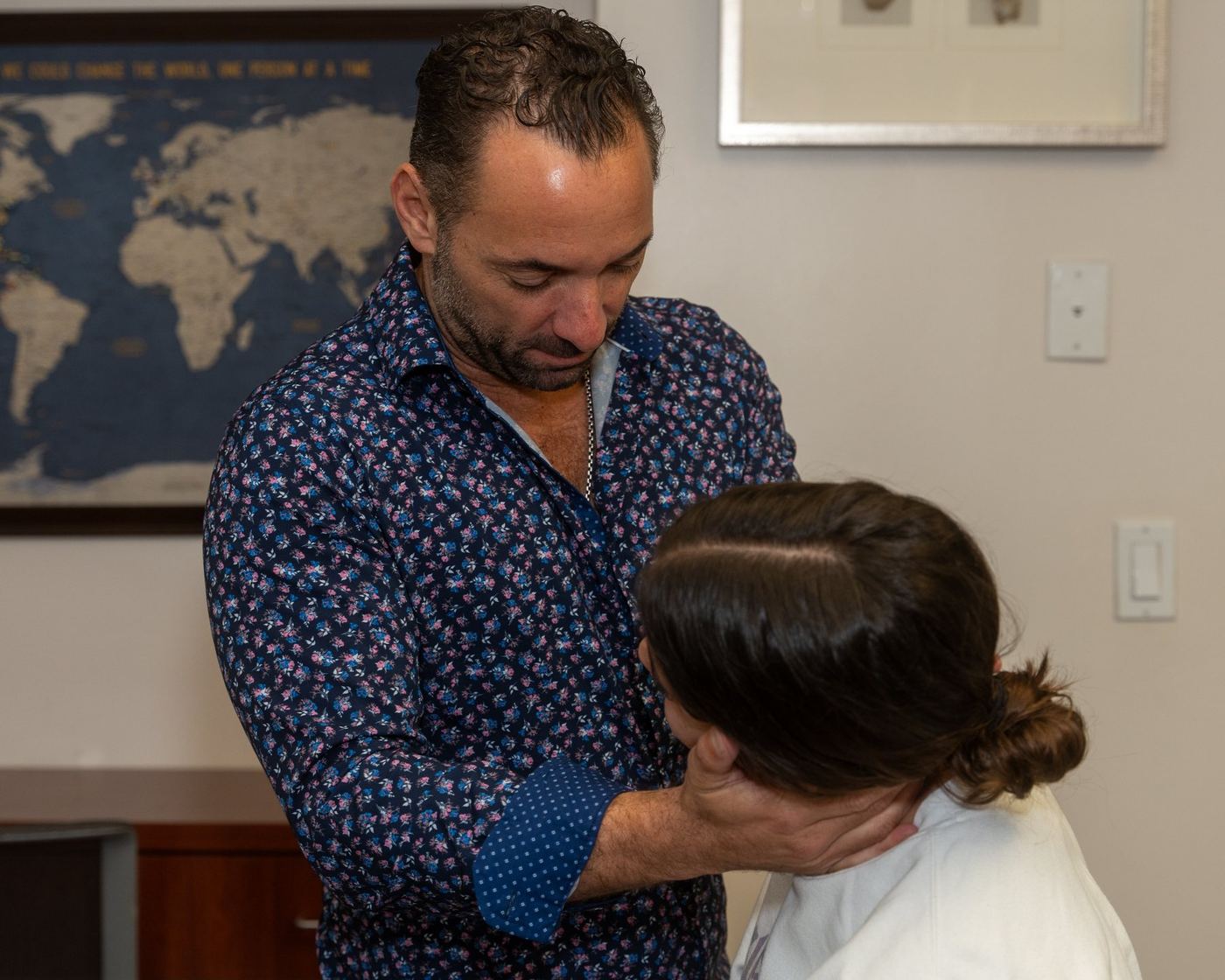Dr. Edward Esposito cradling a patient's head and neck with both hands during an assessment.