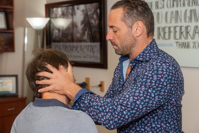 Dr. Esposito supporting a patient's neck with both hands during an assessment.