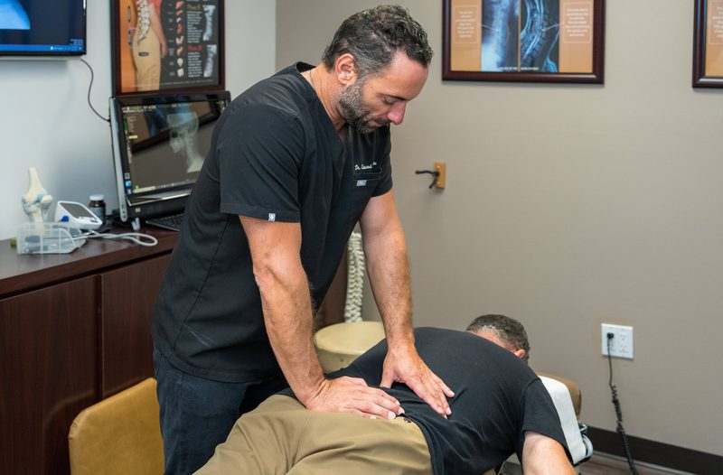 Dr. Edward Esposito performing a hands-on lower back adjustment on a patient.