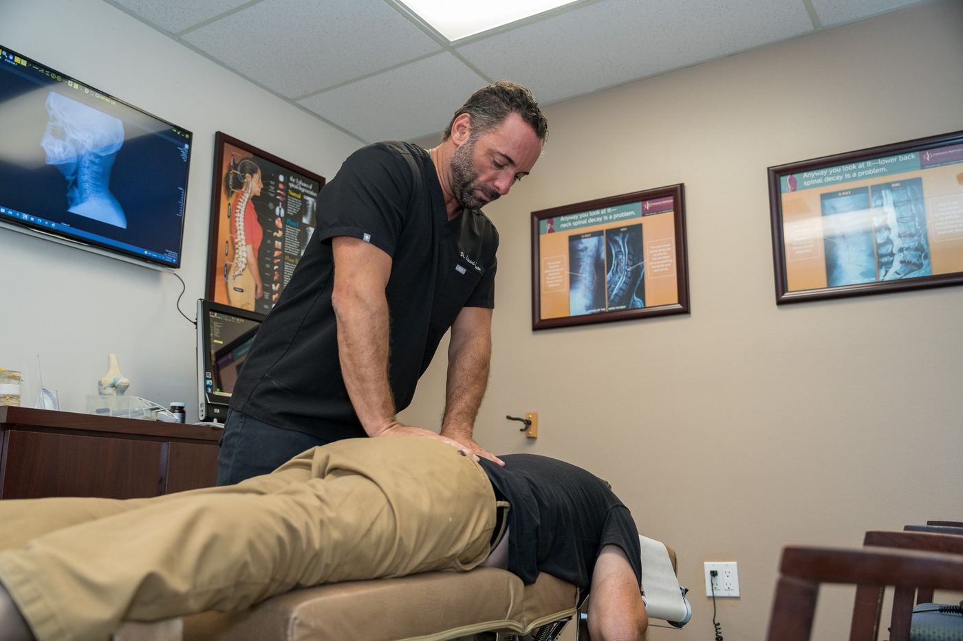 Dr. Edward Esposito applying pressure to a patient's lower back while guiding a leg stretch.