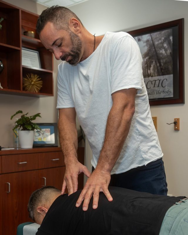 Dr. Esposito performing a two-handed adjustment on a patient's upper back.