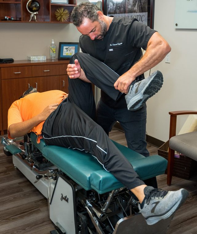 Dr. Esposito guiding a patient's leg through the Cox Flexion-Distraction table.