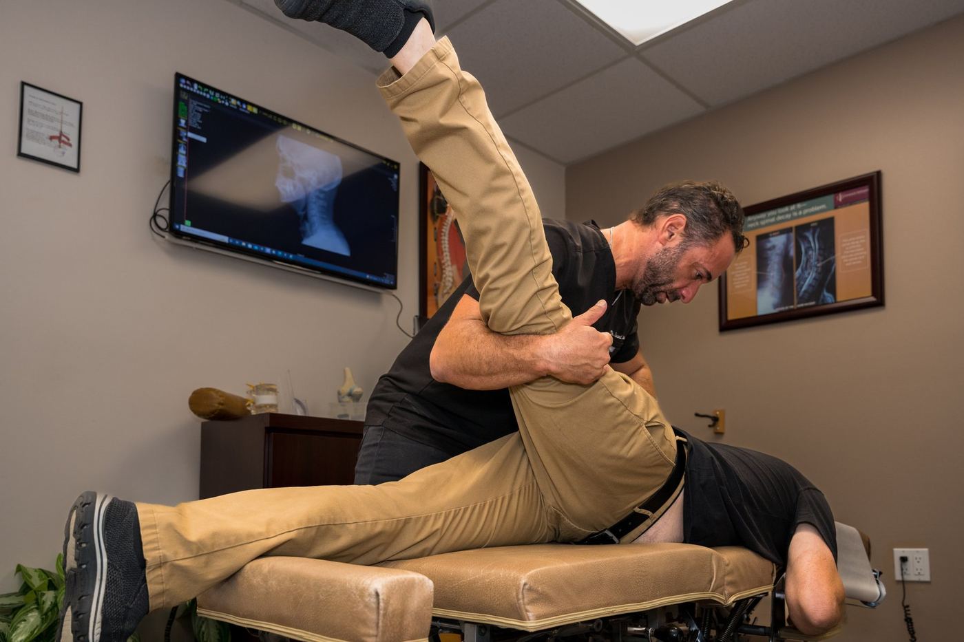 Dr. Edward Esposito assisting a patient through a shoulder and arm stretch in the office.