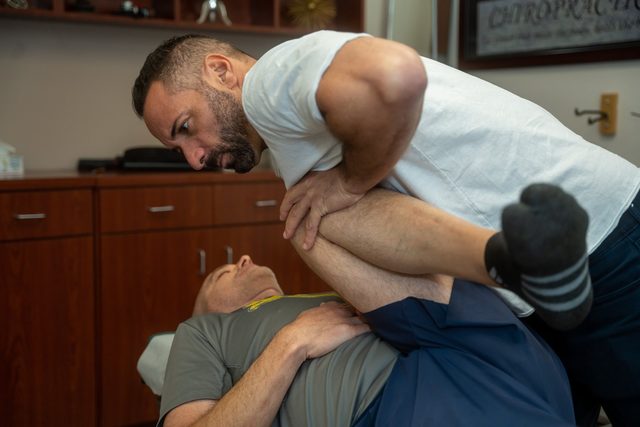 Dr. Esposito guiding a patient through an assisted knee and hip stretch.