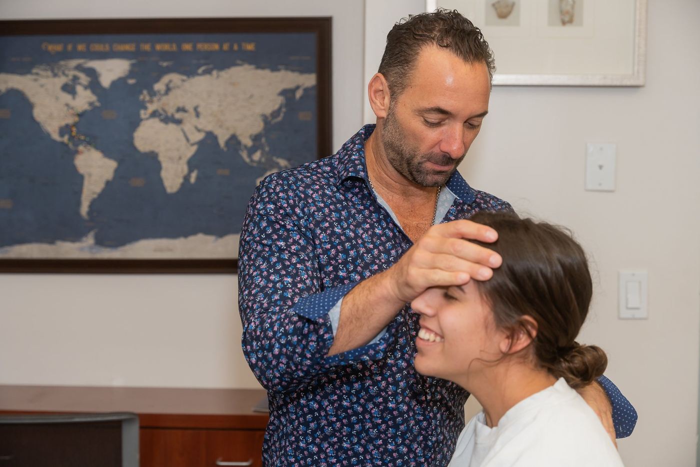 Dr. Edward Esposito gently assessing a smiling patient at Miami Chiropractic.