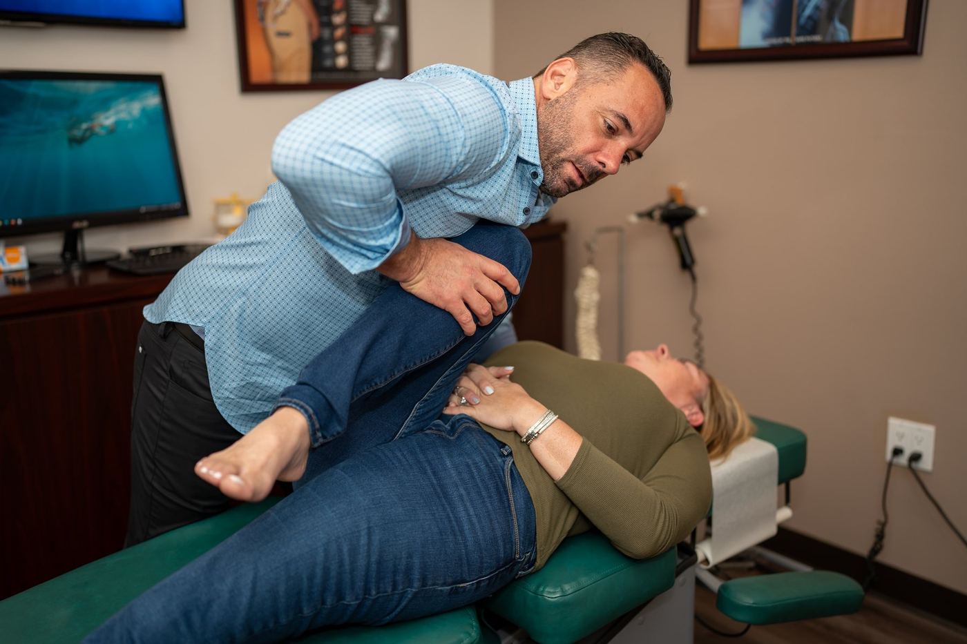 Dr. Edward Esposito performing a hip and knee stretch with a patient during an office visit.