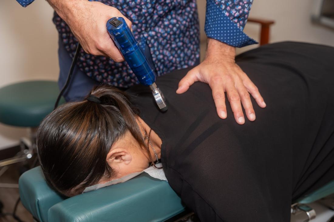 Dr. Edward Esposito applying a handheld adjusting instrument near a patient's neck.