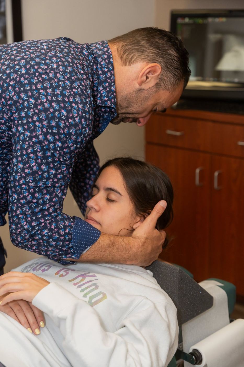 Dr. Edward Esposito cradling a patient's head and jaw during a consultation.
