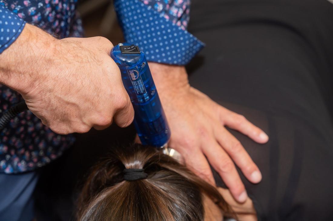Dr. Edward Esposito treating a patient with spinal imaging displayed on a screen behind him.